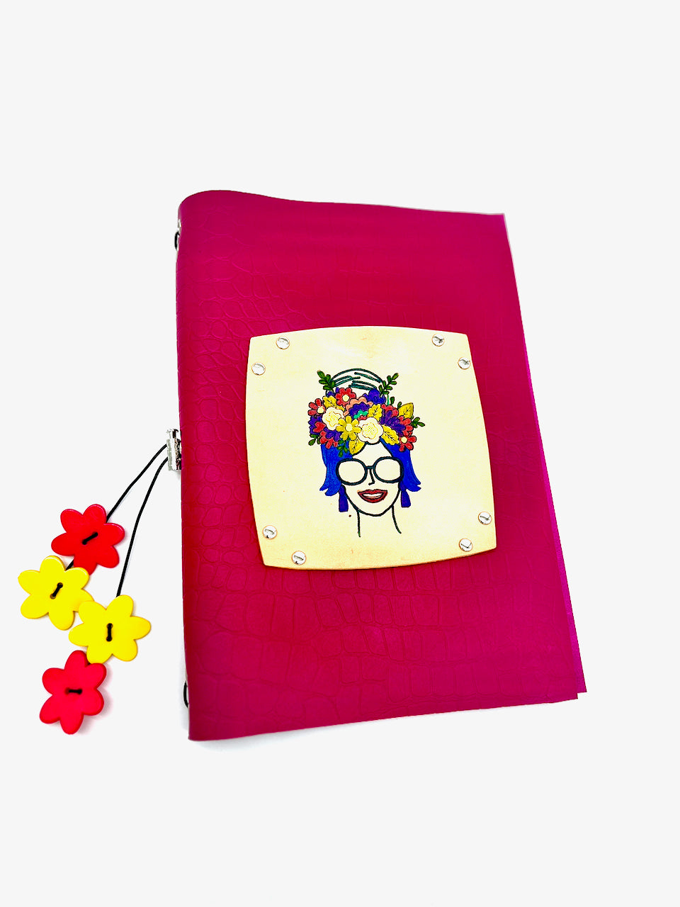 A hot pink leather journal with a crocodile print embossed on it. Features a hand-colored floral centerpiece, with plastic flower beads hanging from the elastic closure.