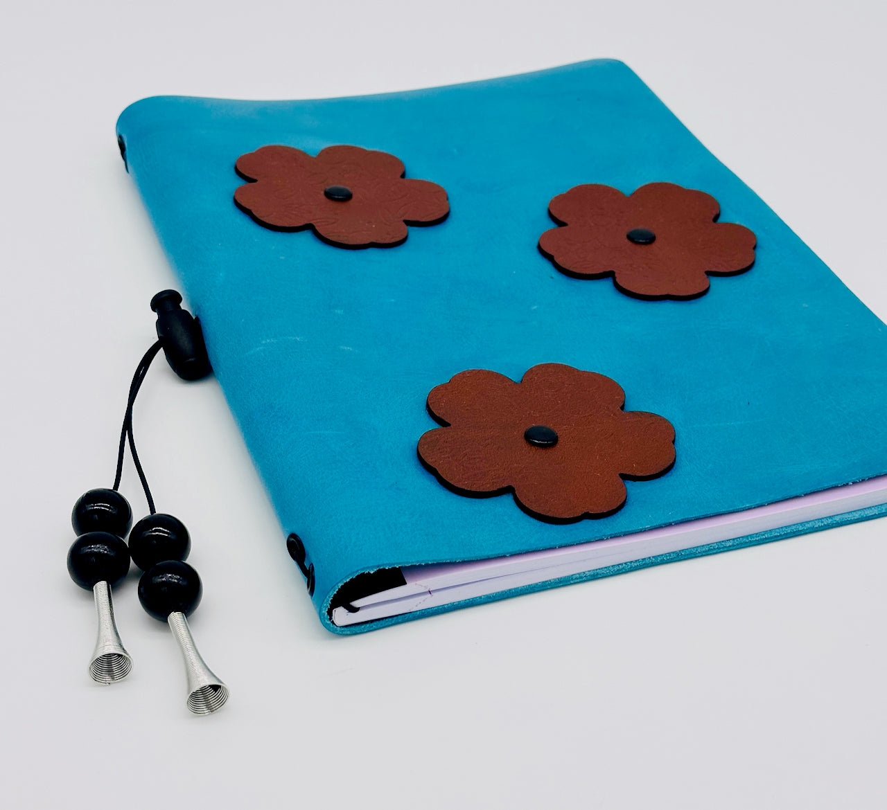 low angled view of a Blue Flowered Leather bound Journal with a beaded tassel