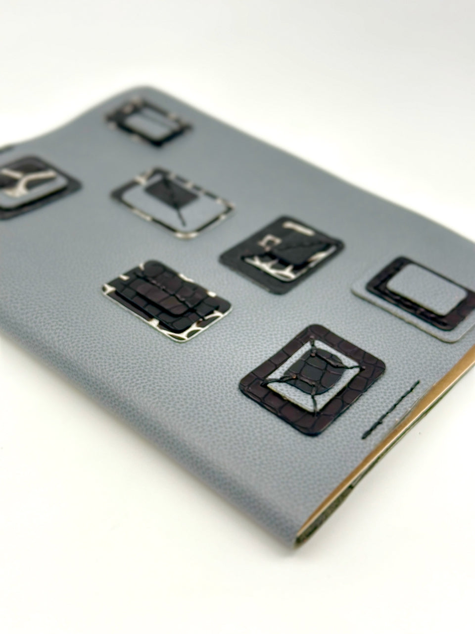 Blue-leather-journal-cover-with-blue-and-black-squares-portrait-focus diagonal angle