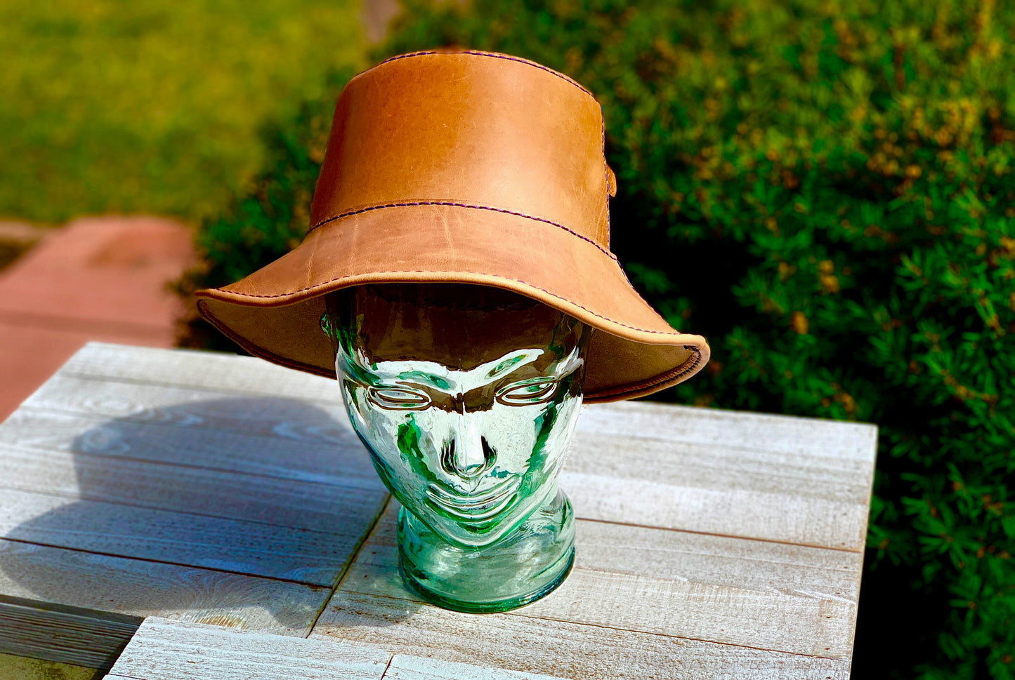 tan leather bucket hat on glass mannequin head