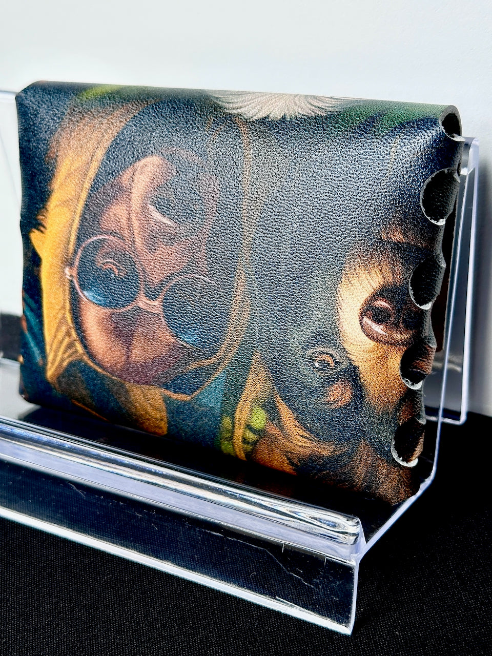Leather wallet with dog in sunglasses design on a stand against a white background