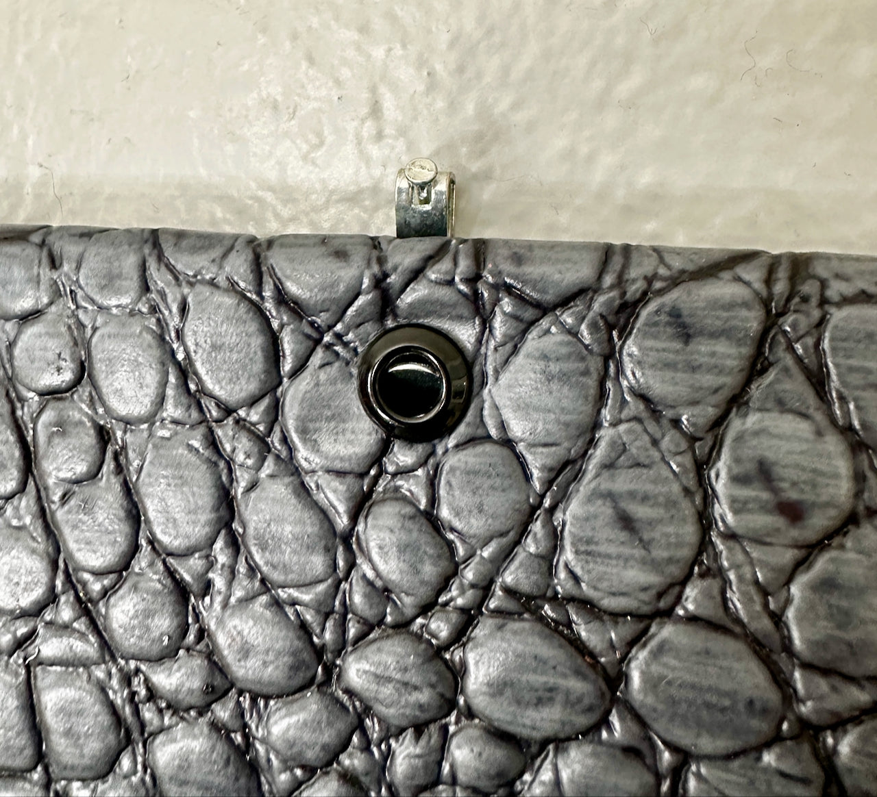 Close-up of an eyelet on textured leather with pebble pattern on a neutral background