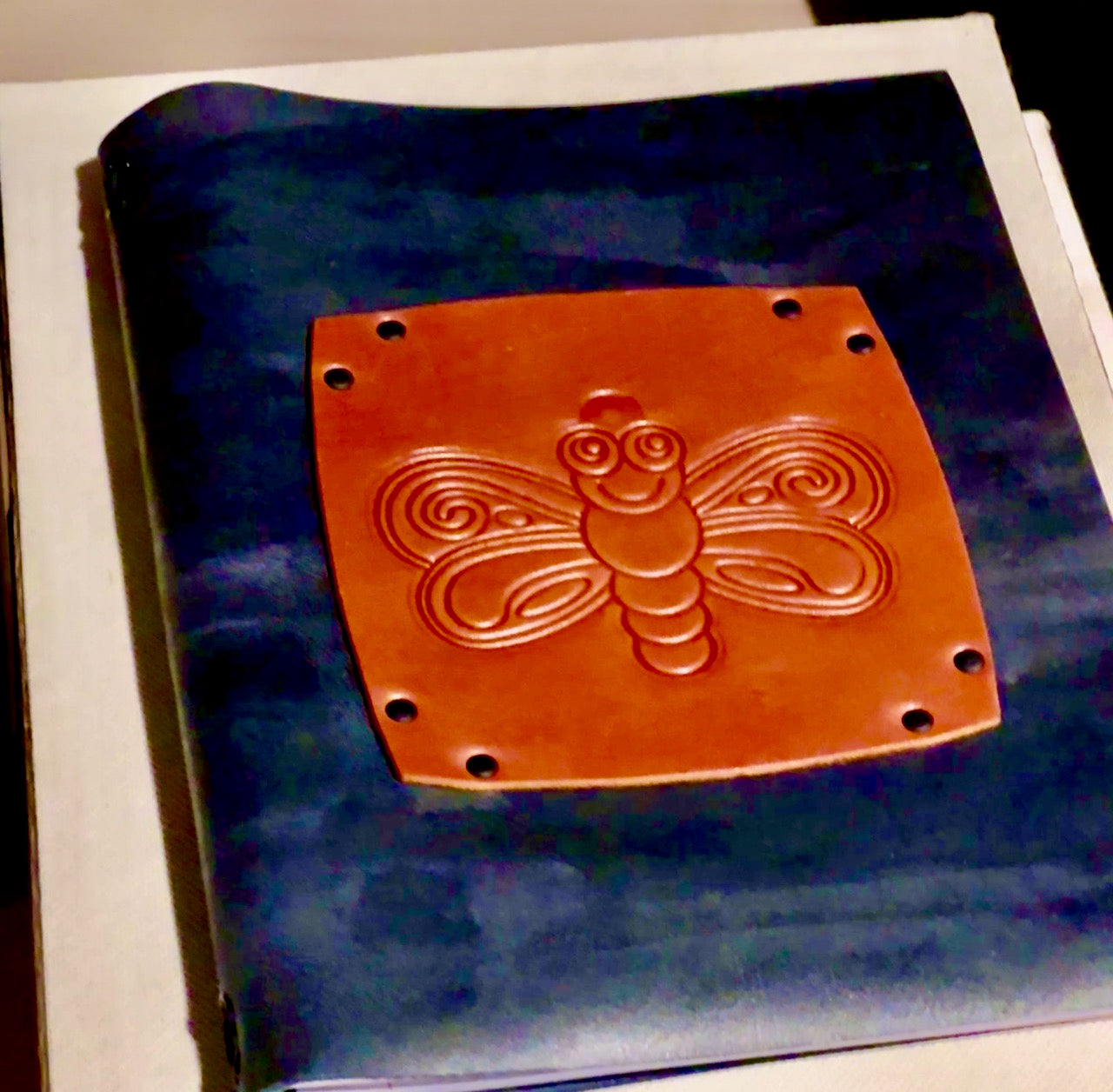A handmade leather journal with an embossed butterfly design on the front cover.