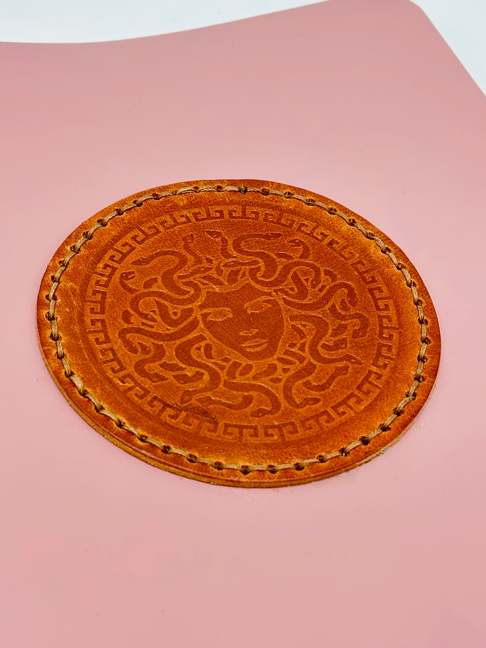 Close up of leather medusa embossed medallion on pink leather journal