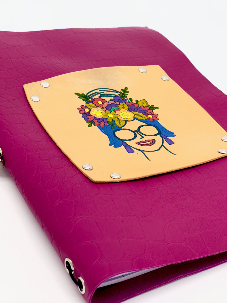detail of handpainted women with flowers in hair on pink leather journal