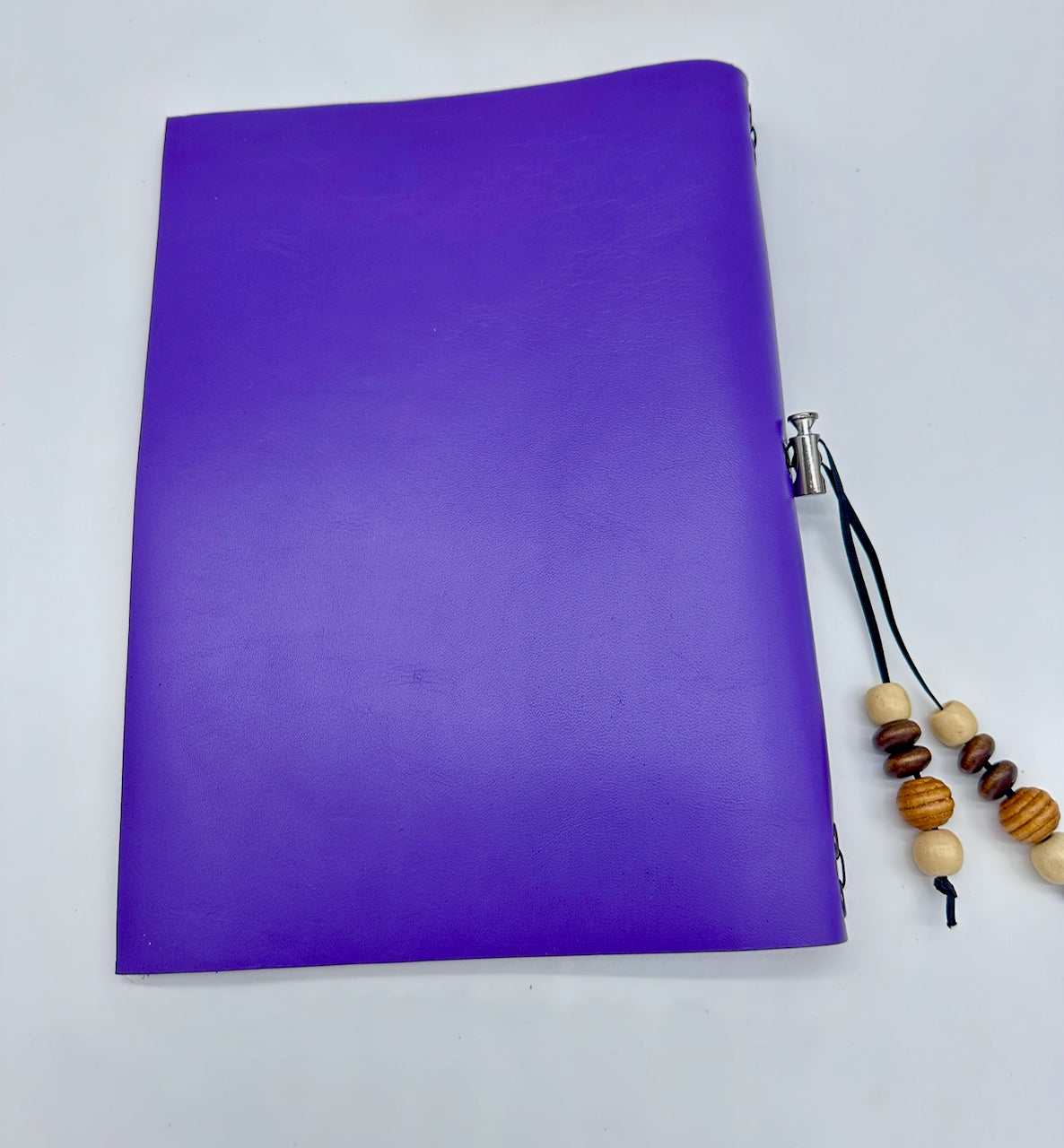 Purple leather notebook back cover with a wooden beaded toggle.