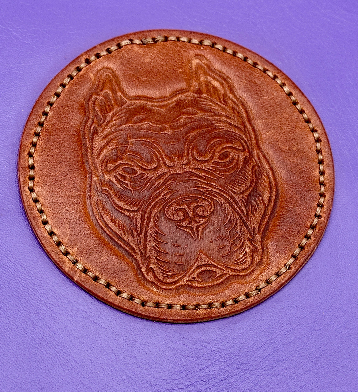 Brown leather patch with a pit bull dog face embossed design on a purple leather journal