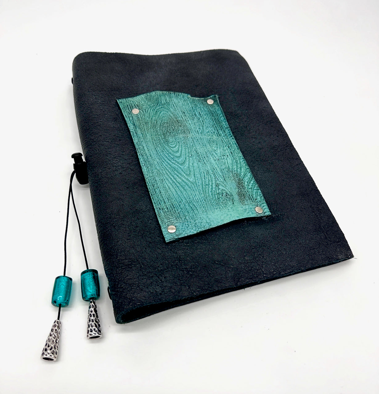 front cover of black and turquoise leather refillable journal with lined paper insert