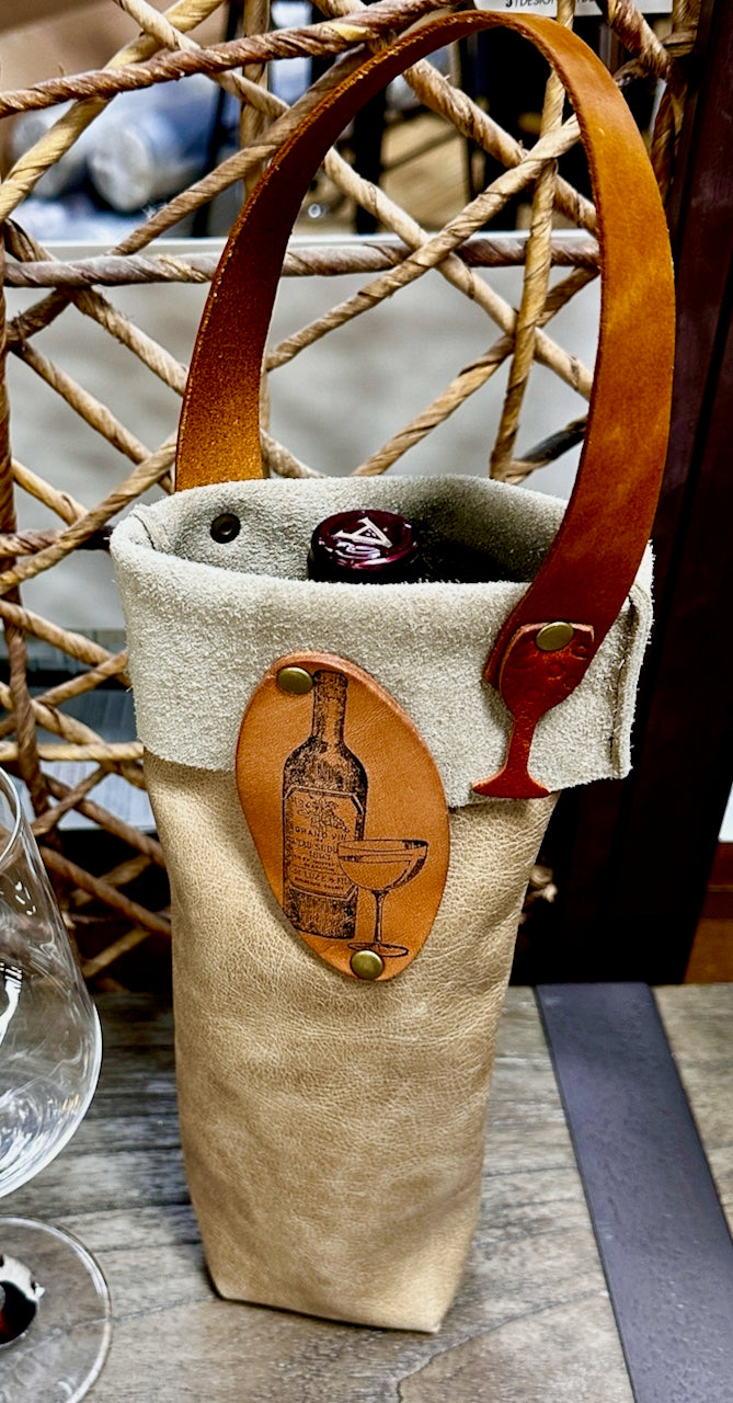 Wine bottle carrier made from leather holds a bottle of wine and sits on a table