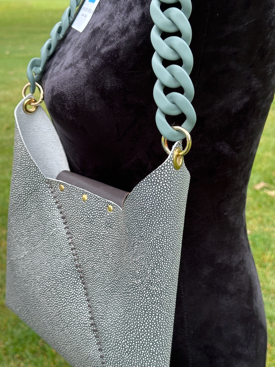 Green textured shagreen leather crossbody handbag with a light green chain strap on mannequin.