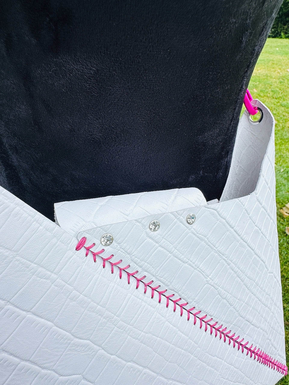 back detail of rhinestone rivets on a white leather crossbody handbag on a black velvet mannequin
