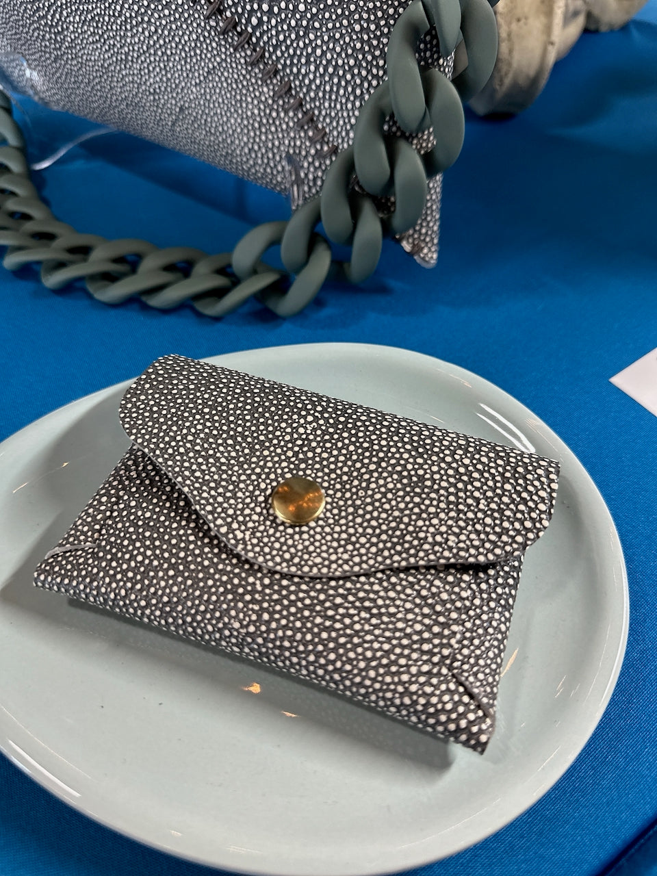 green shagreen leather textured wallet on a white plate with a blue background