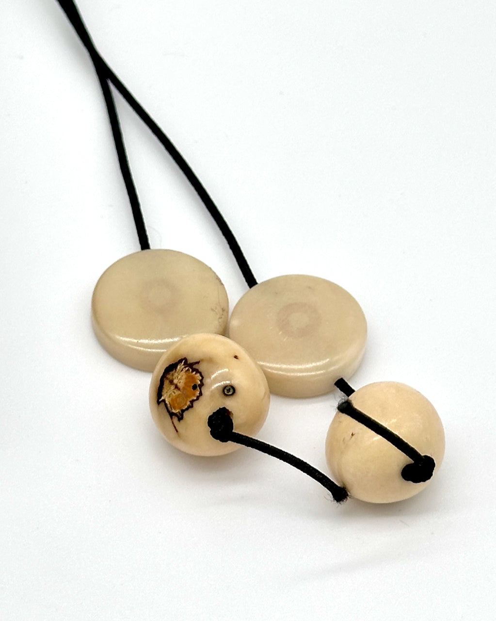 Black elastic toggle with beige beads on a white background