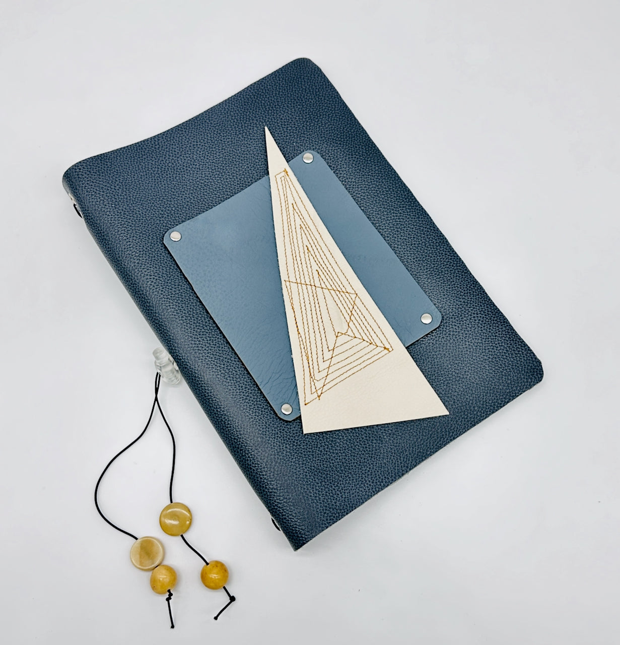 Blue leather notebook journal with a geometric design on a light gray background