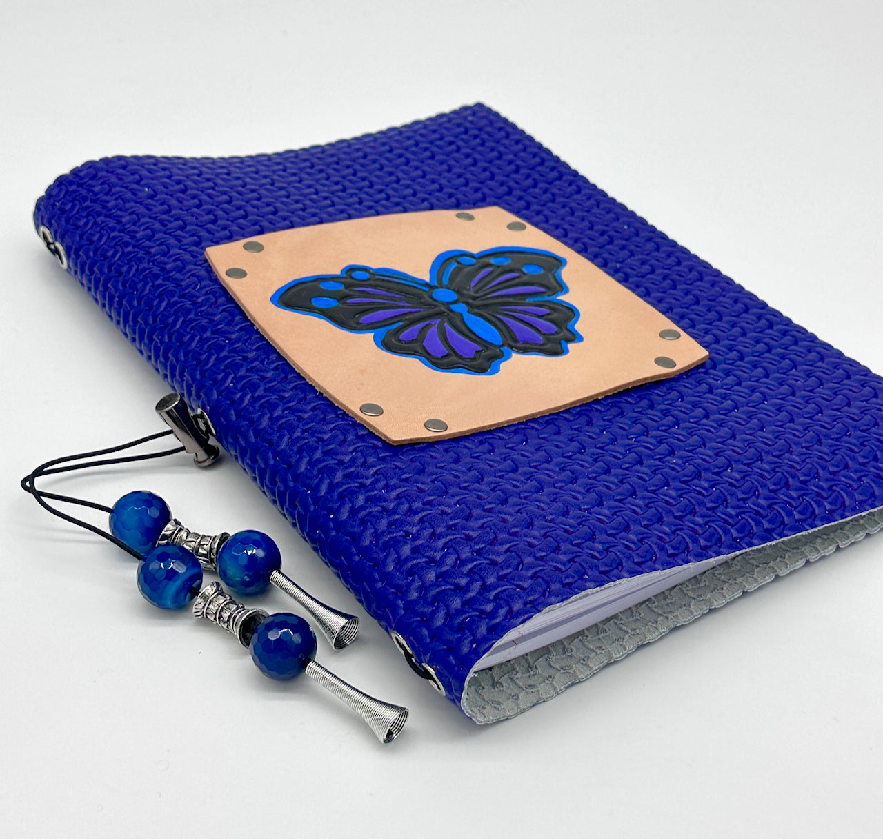 low angle photo of a blue leather covered journal with a butterfly on the cover