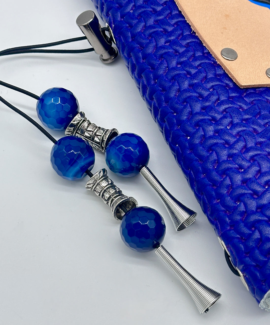 extreme close up of blue glass beads and silver spacer beads on tassel of leather bound journal.