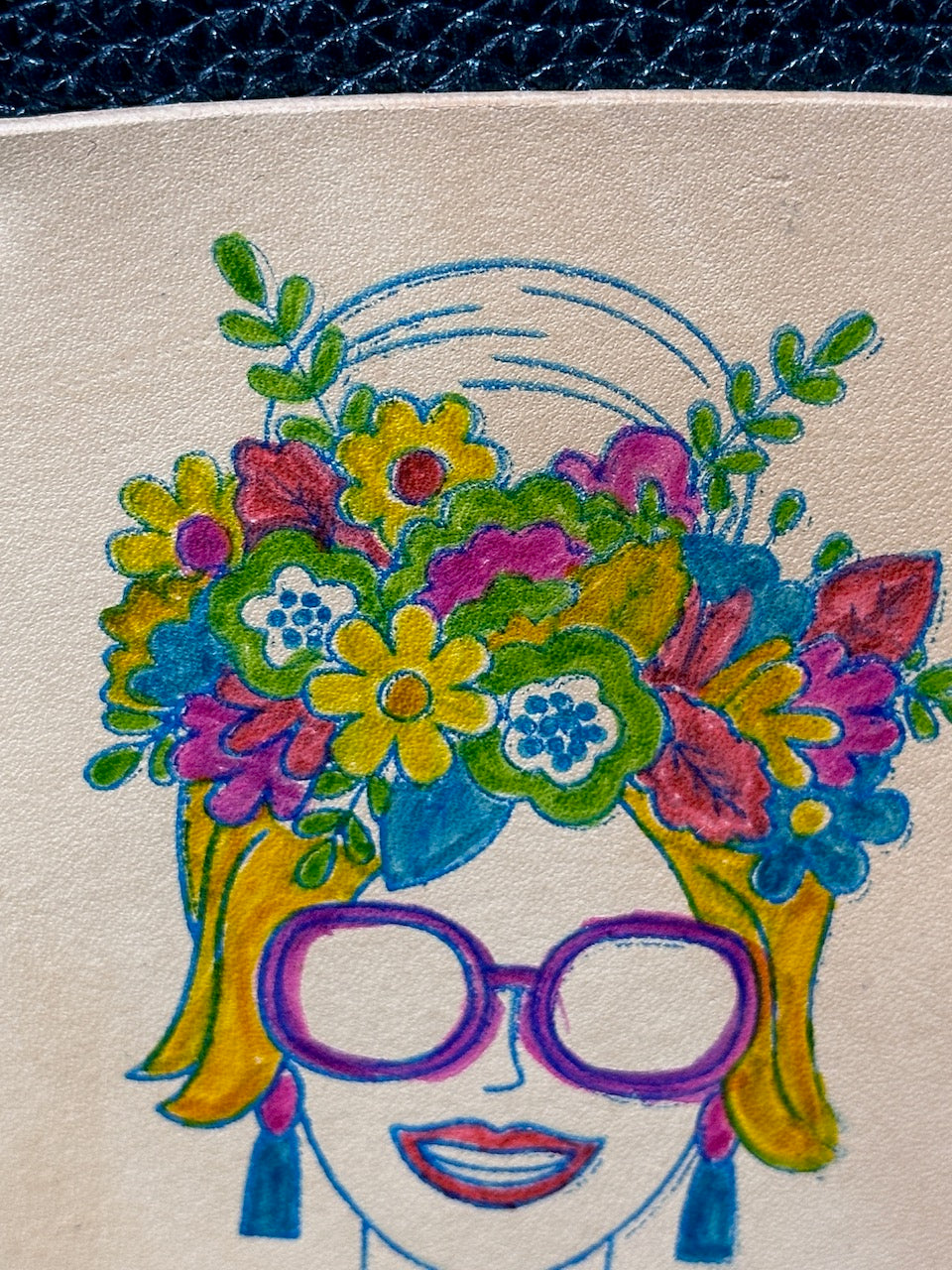 close up detail of hand painted woman with flowers in her hair on leather journal made by Undercover Popular Leather Goods