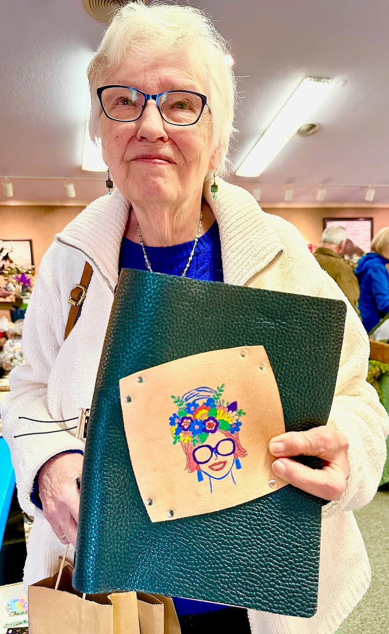 older woman shows us her purchase of a green leather journal