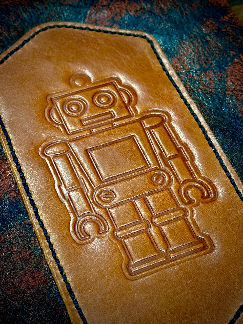 close up detail of the embossed robot on brown leather on the robbie roboto refillable leather journal from undercover popular leather goods