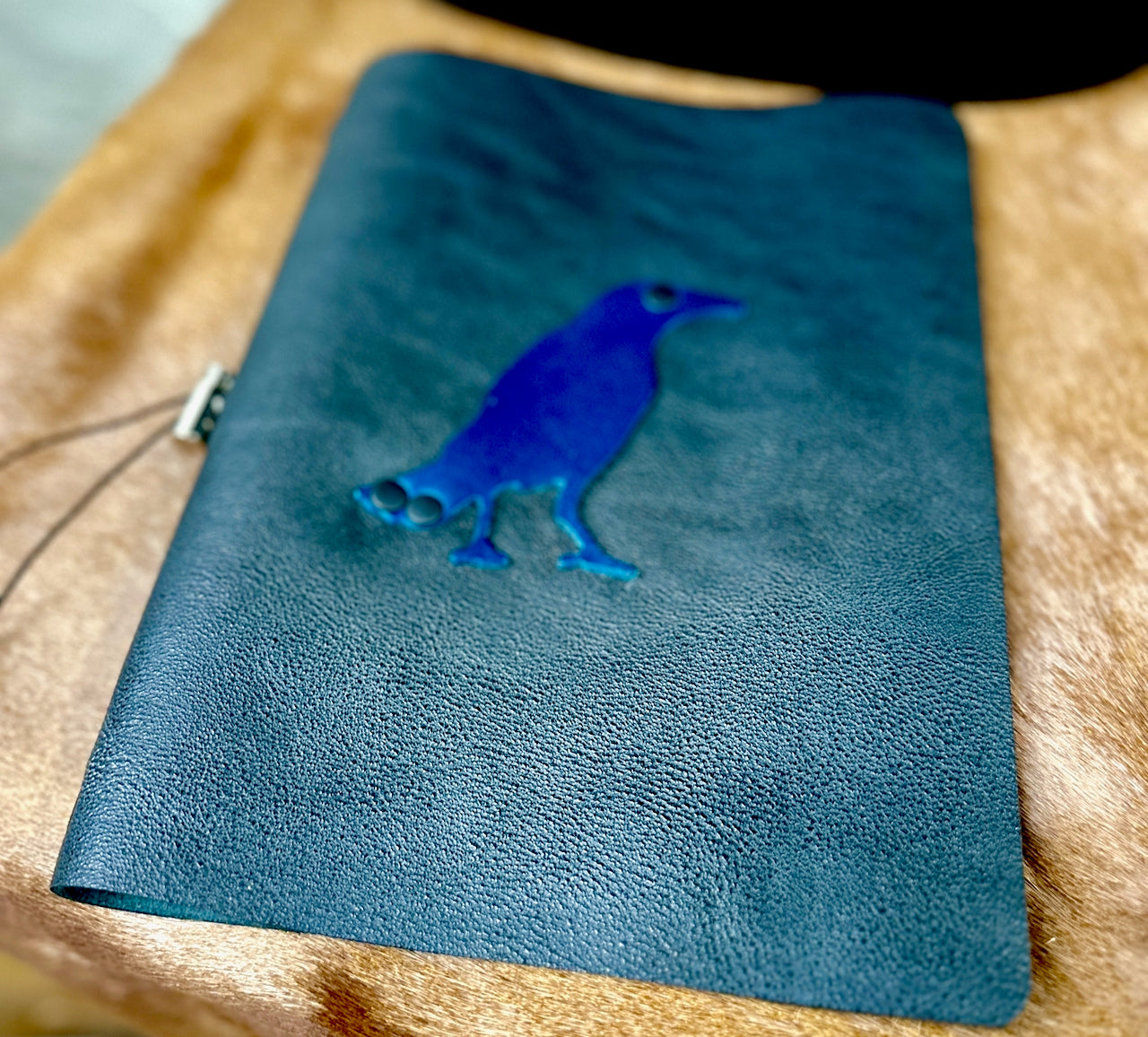 soft focus front cover of leather journal with crow or raven on the front