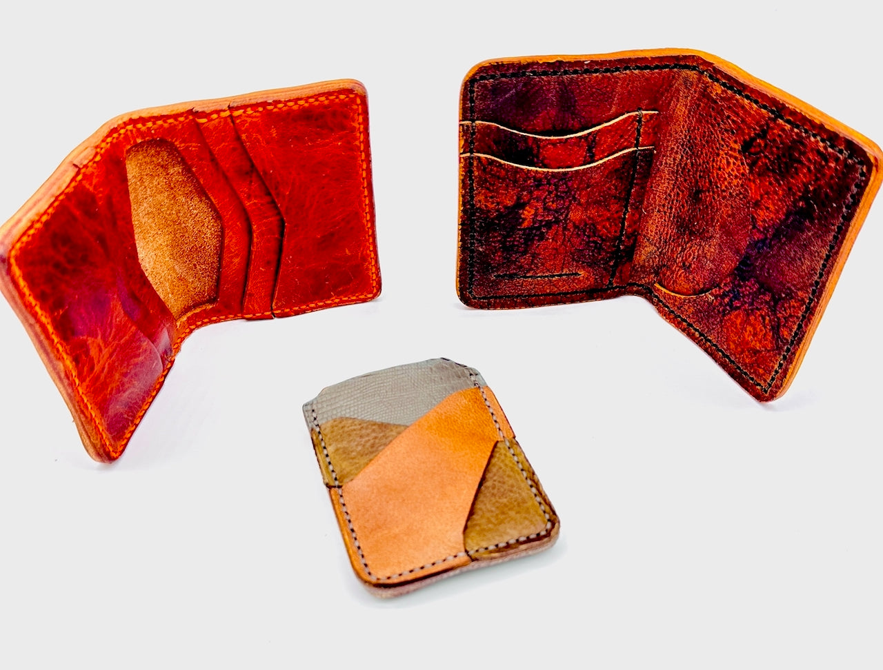 Three leather wallets in different designs on a light gray background