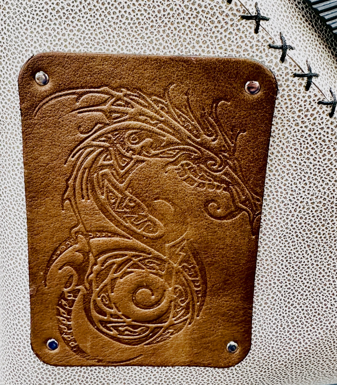 Green leather purse with embossed dragon design on a textured gray background