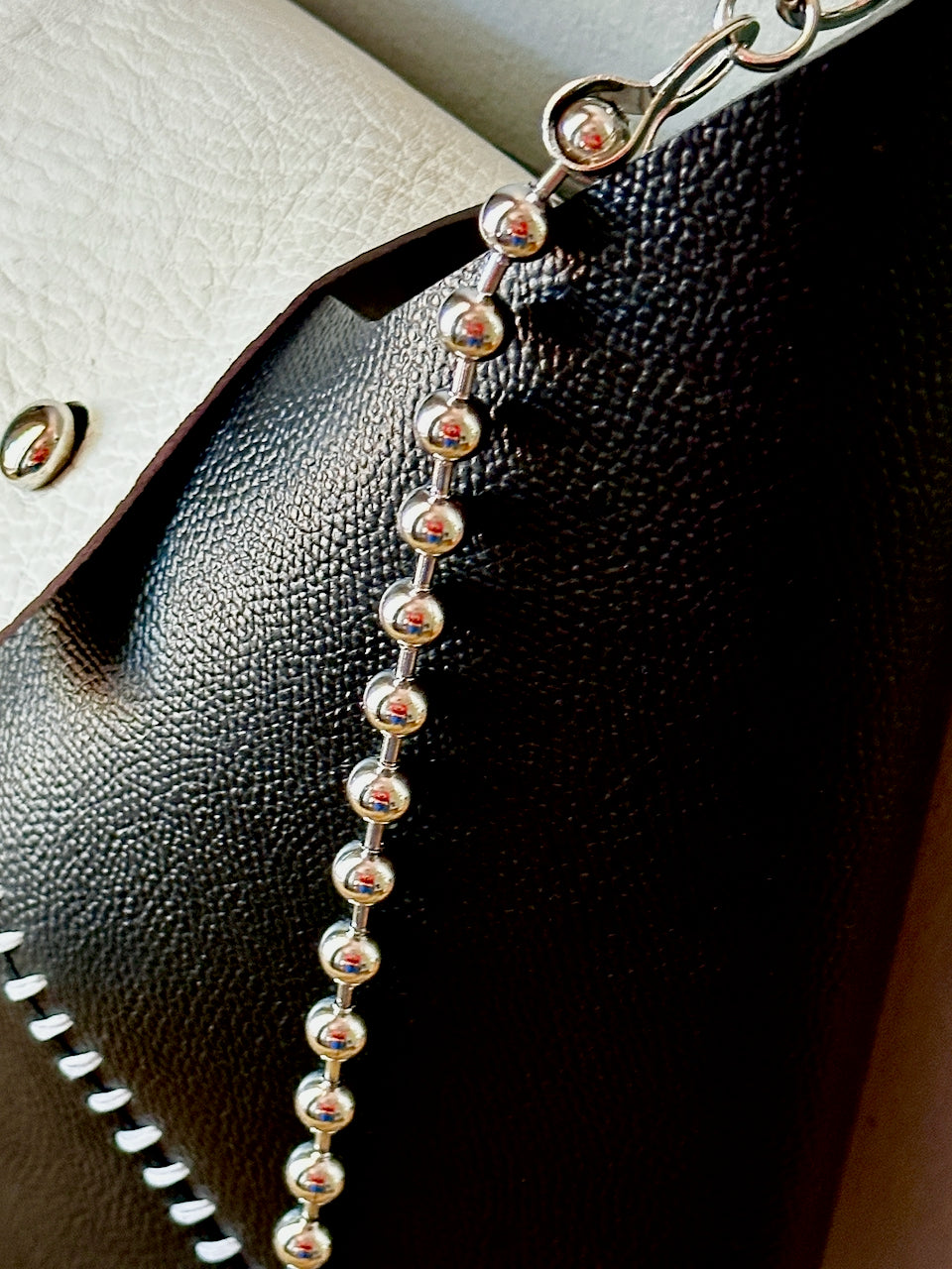 Silver beaded chain on a textured leather purse