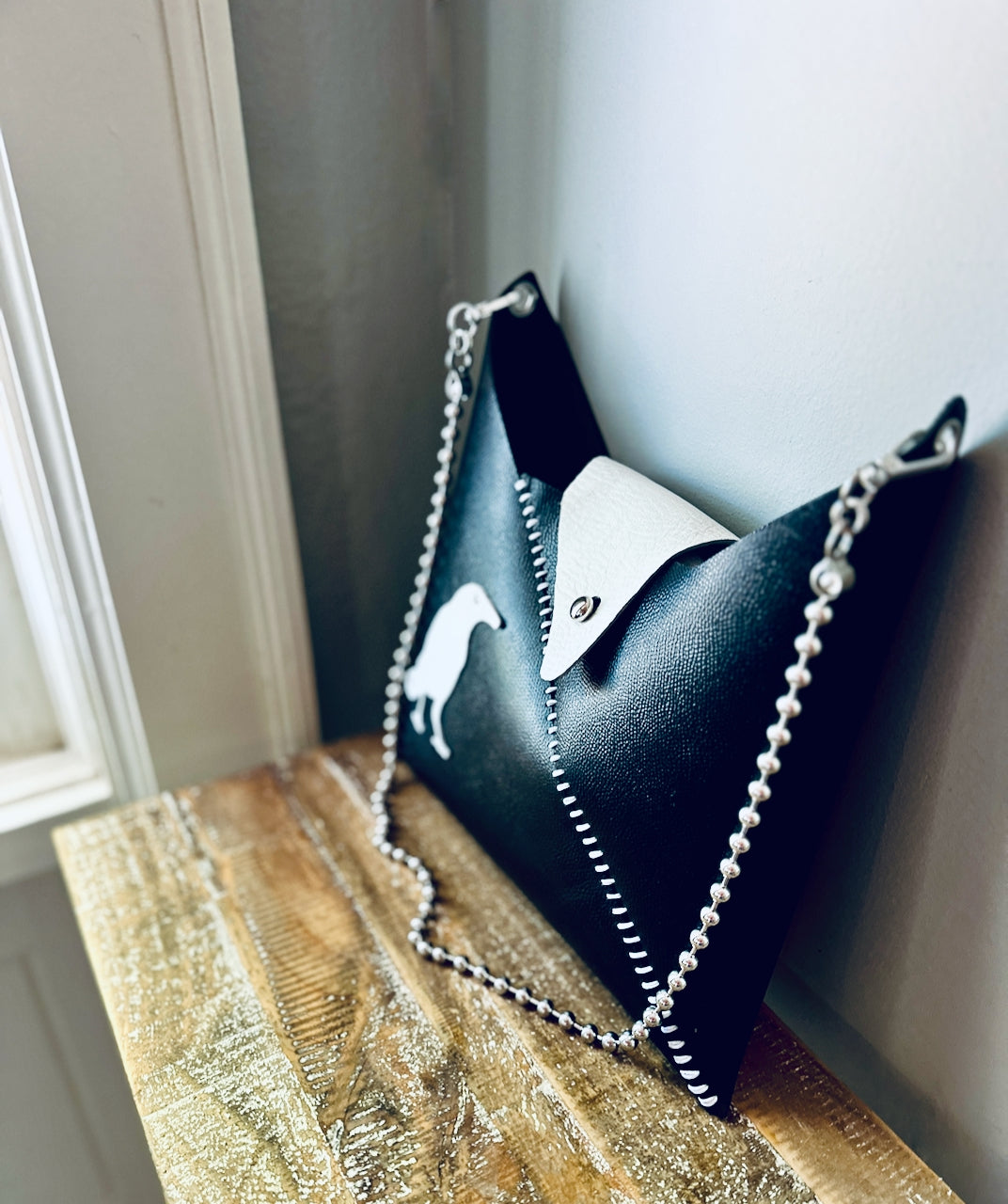 Black handbag with a chain detail on a wooden surface