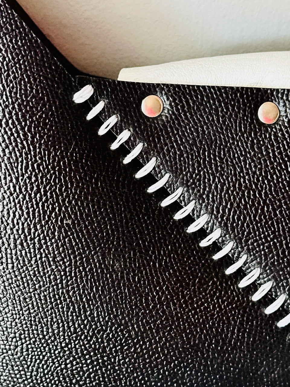 Close-up of a black leather purse with white stitching