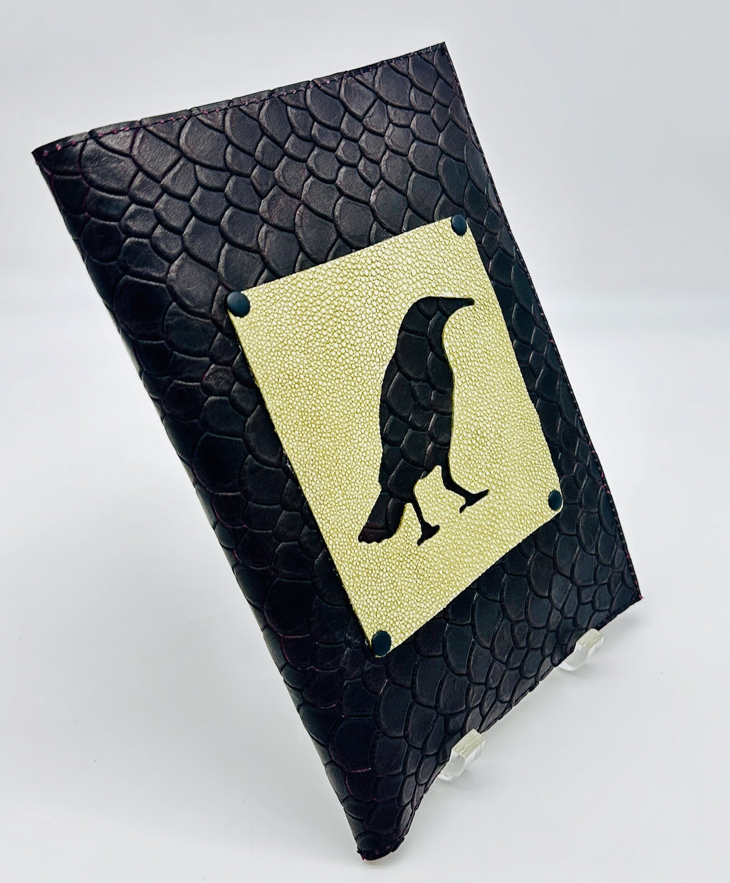 Black leather notebook with a green shagreen patch featuring a black silhouette of a bird on a white background