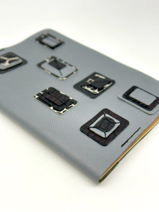 Blue-leather-journal-cover-with-blue-and-black-squares-portrait-focus diagonal angle