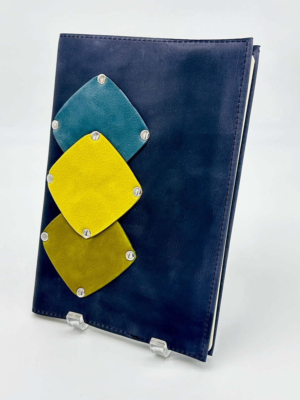 Blue notebook with geometric yellow, green and teal patches on a white background