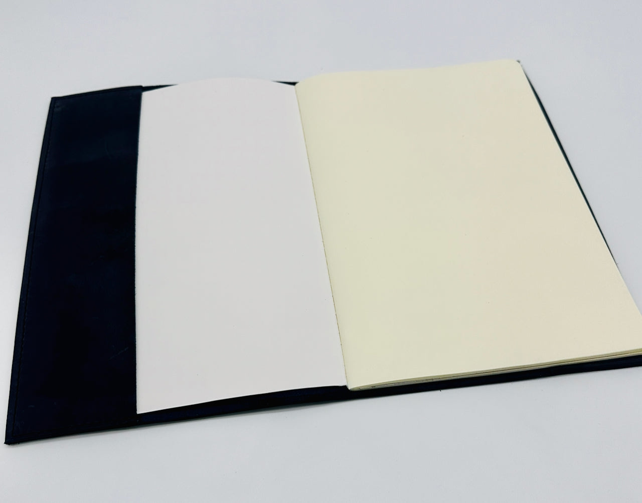 Open journal book with inside flap and beige paper insert on a light gray background