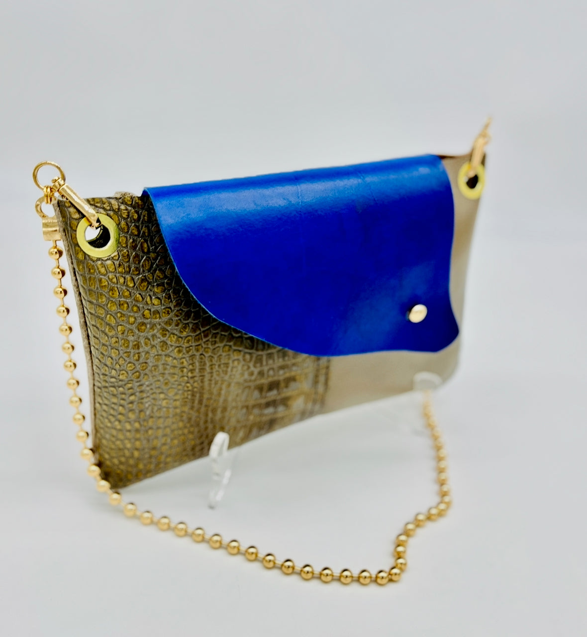 Handbag with blue flap and gold chain on a white background