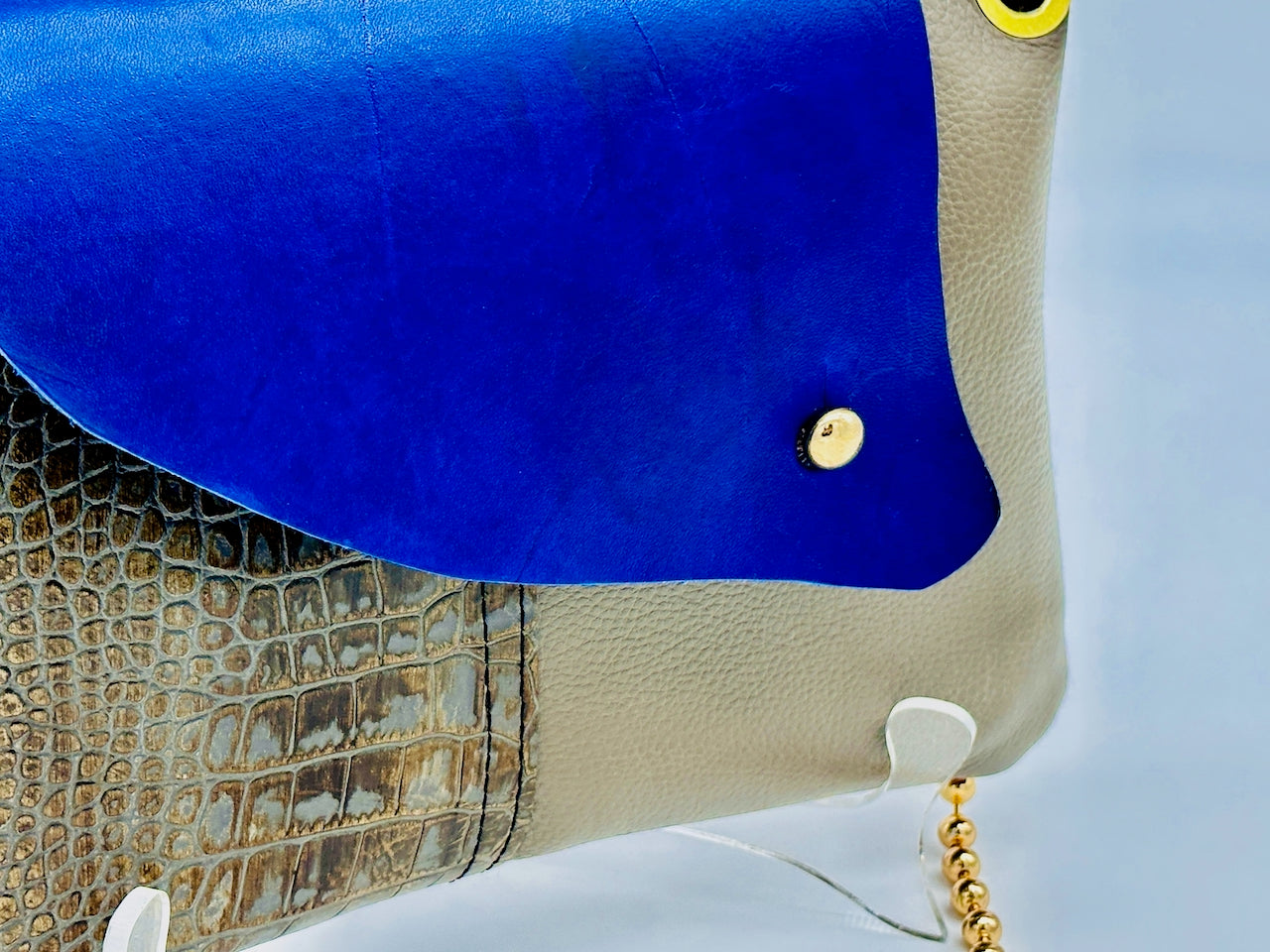 Close-up of a blue and beige handbag with a gold chain.