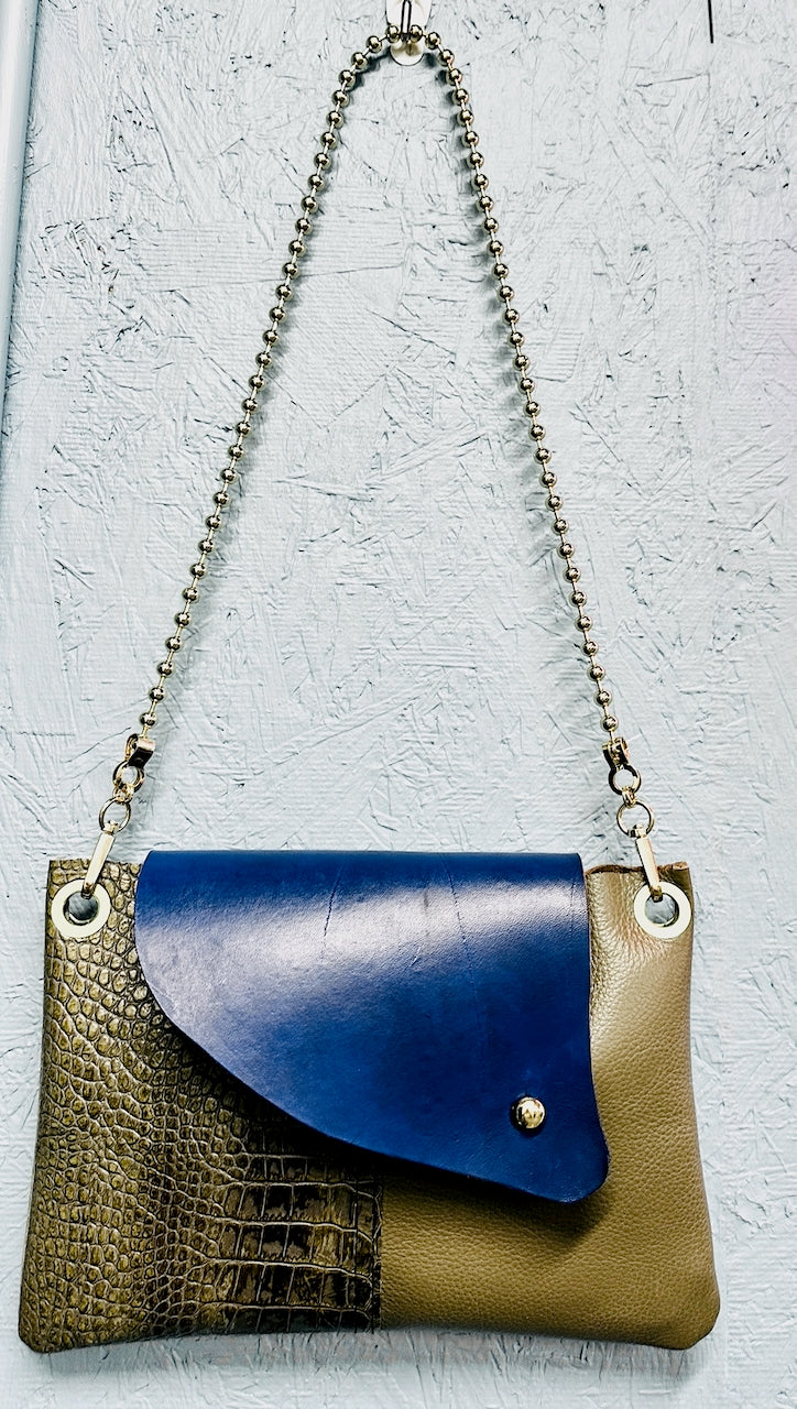Handbag with blue flap and gold chain strap on a textured light blue background