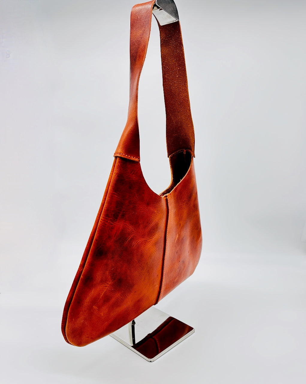 Orange leather bag on a stand against a white background