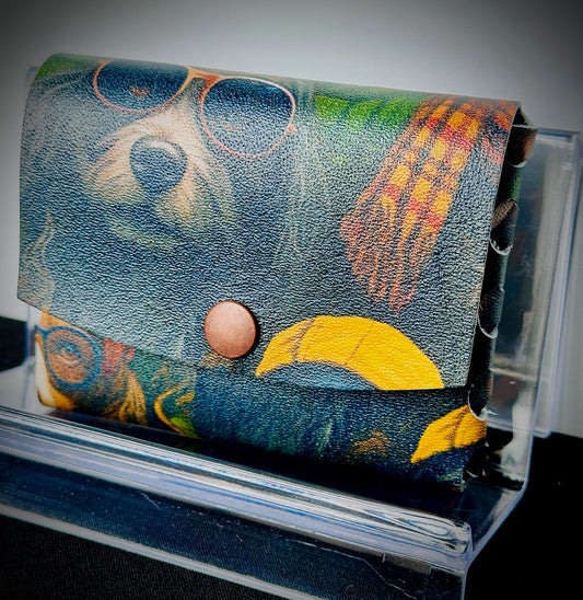 Colorful leather wallet with dogs in sunglasses, with a snap closure on a clear stand.