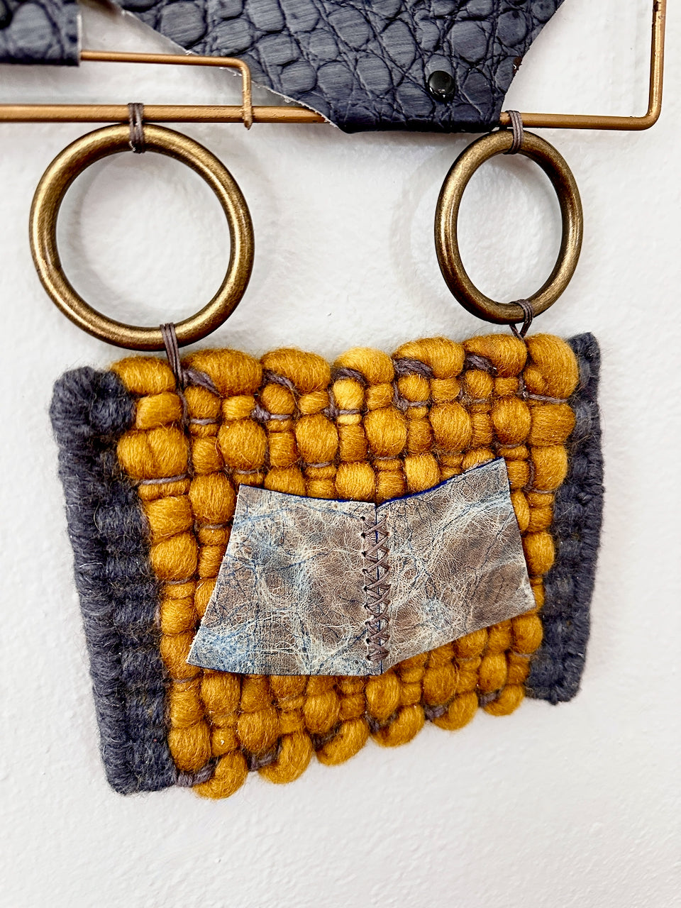Textile art piece with yellow and gray patterns on a white background