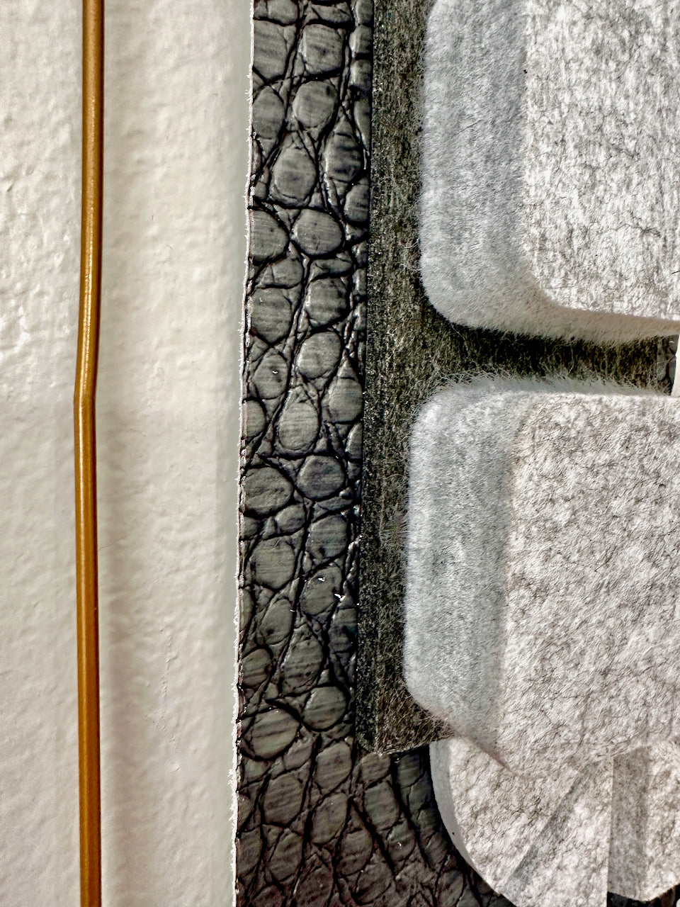 Close-up of a textured wall hanging with a gold frame on the left