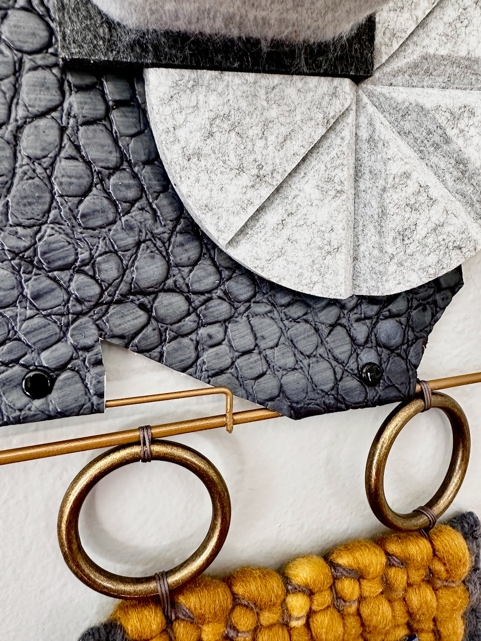 Close-up of textured fabric with geometric patterns and gold rings on a neutral background