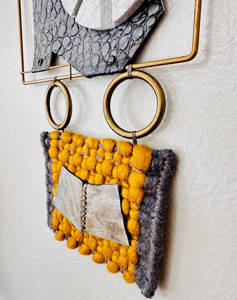 Textile wall hanging created by Undercover Popular Leather Goods with yellow and gray geometric design on a white background