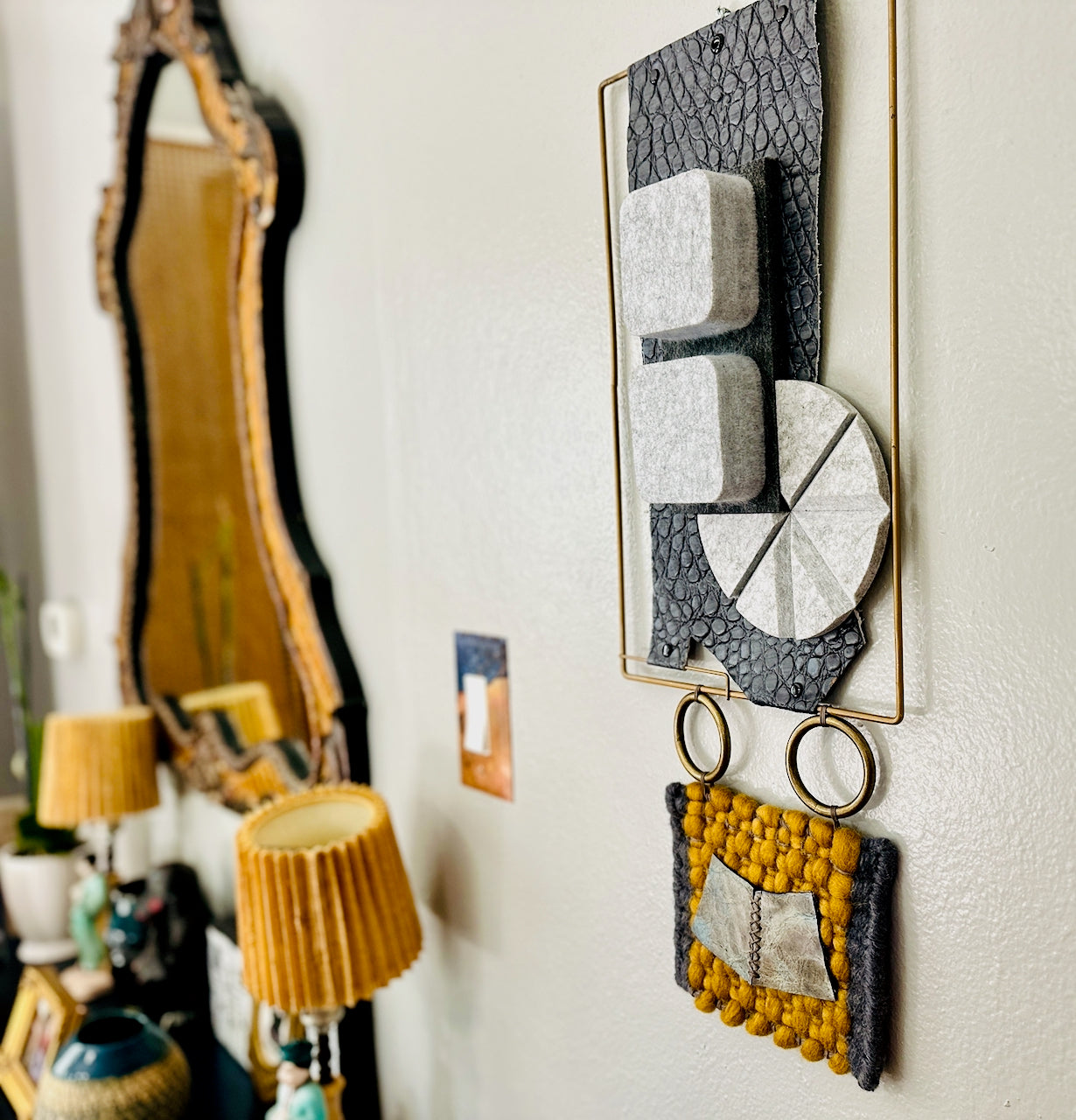 Decorative wall art with geometric patterns and a mirror in a room setting.