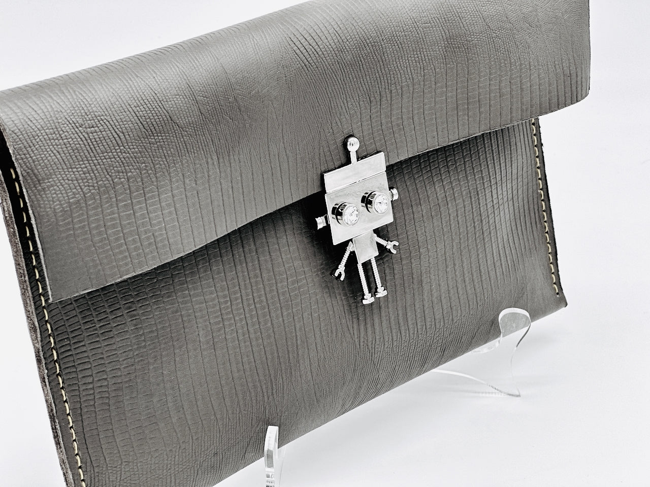Gray textured clutch bag with a robot-shaped clasp on a white background