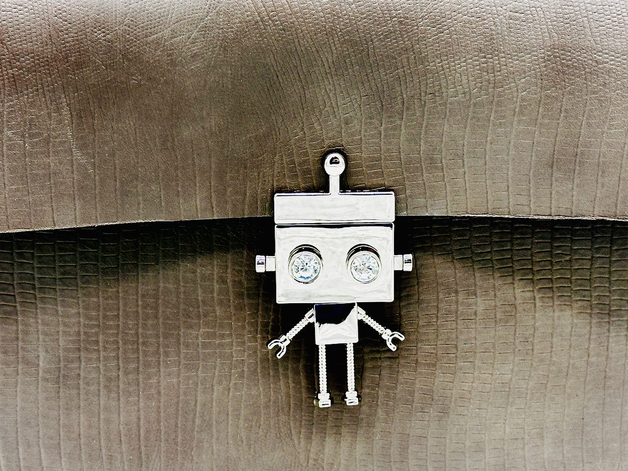Silver robot lock clasp on a textured gray leather clutch purse
