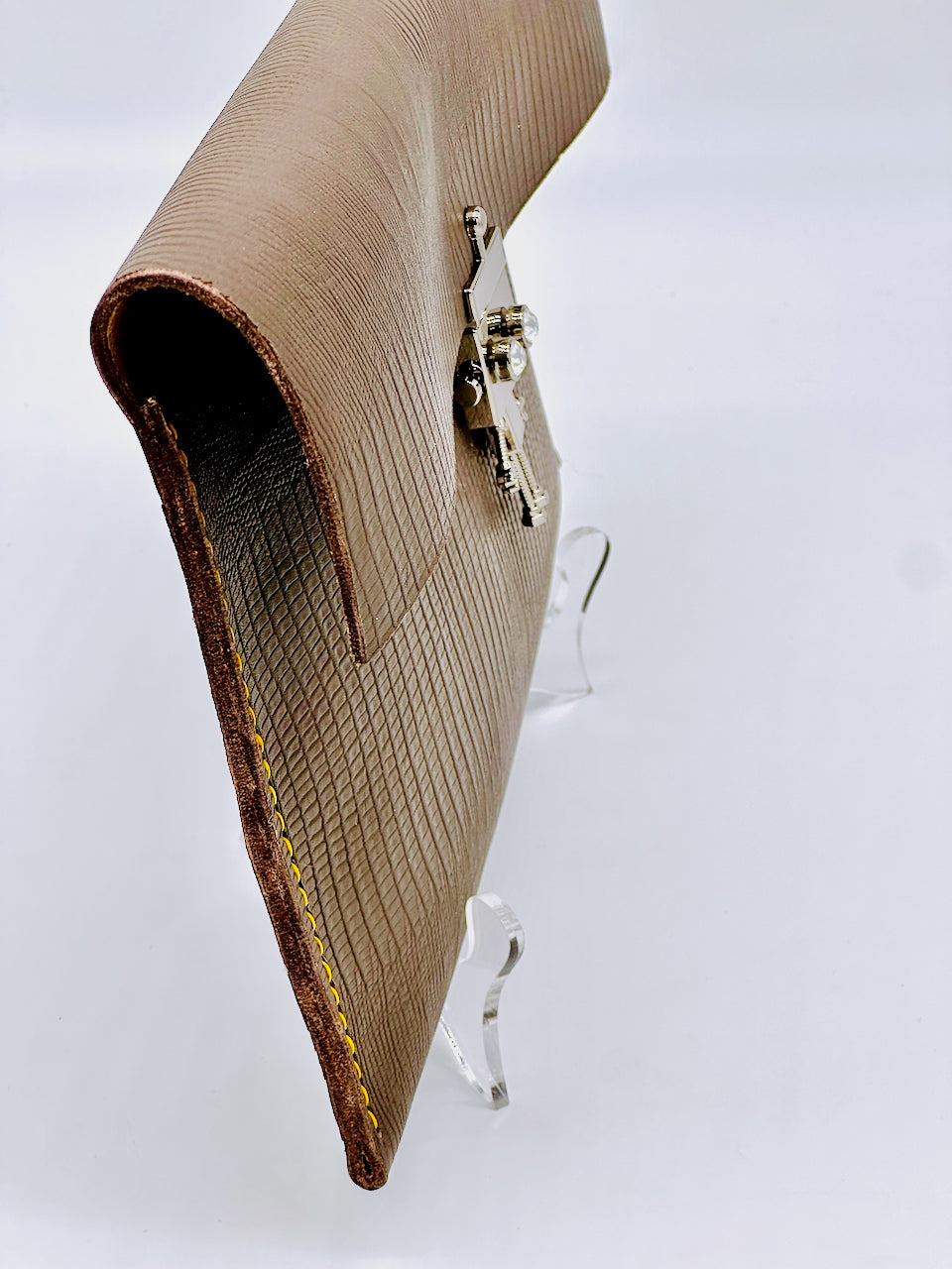 Gray textured leather clutch bag with a silver  robot clasp on a white background