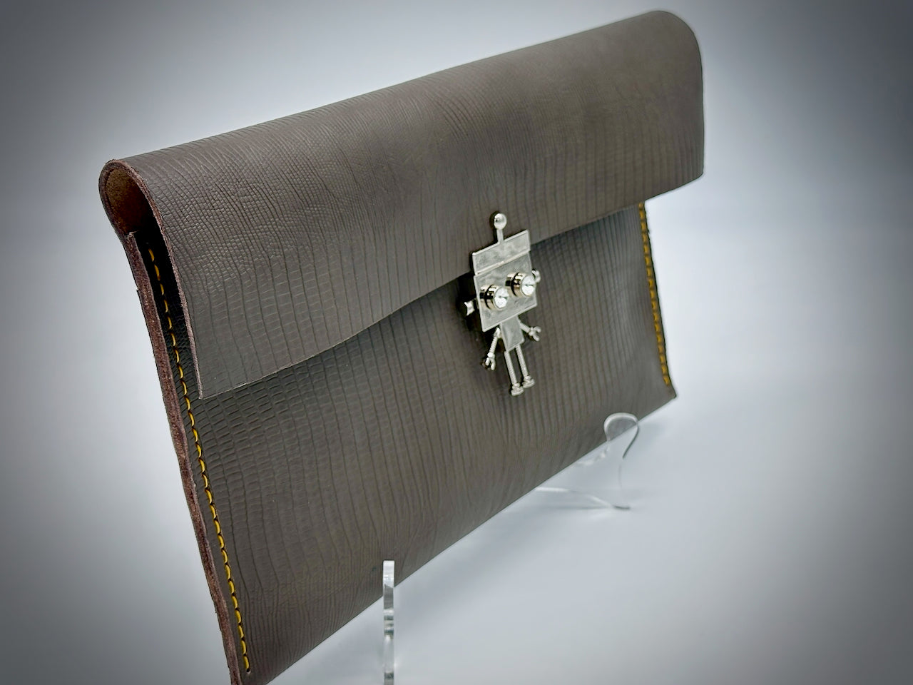 Gray clutch bag with a silver robot clasp on a gray background