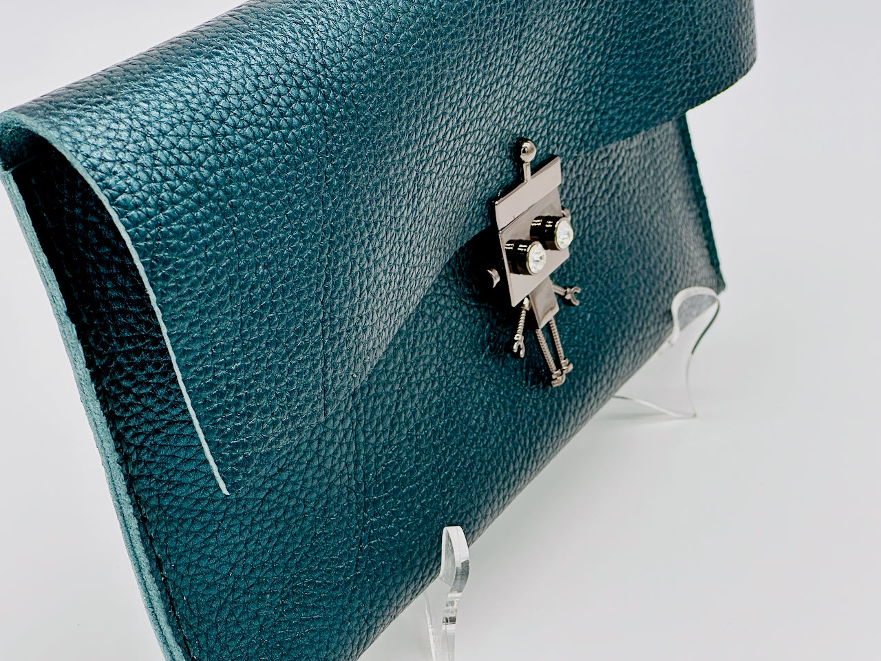 Green metallic leather clutch with a silver robot lock clasp on a white background