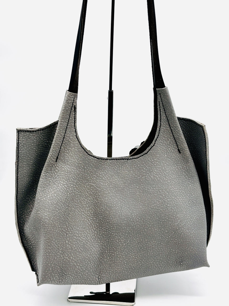 Gray handbag on a stand with a white background