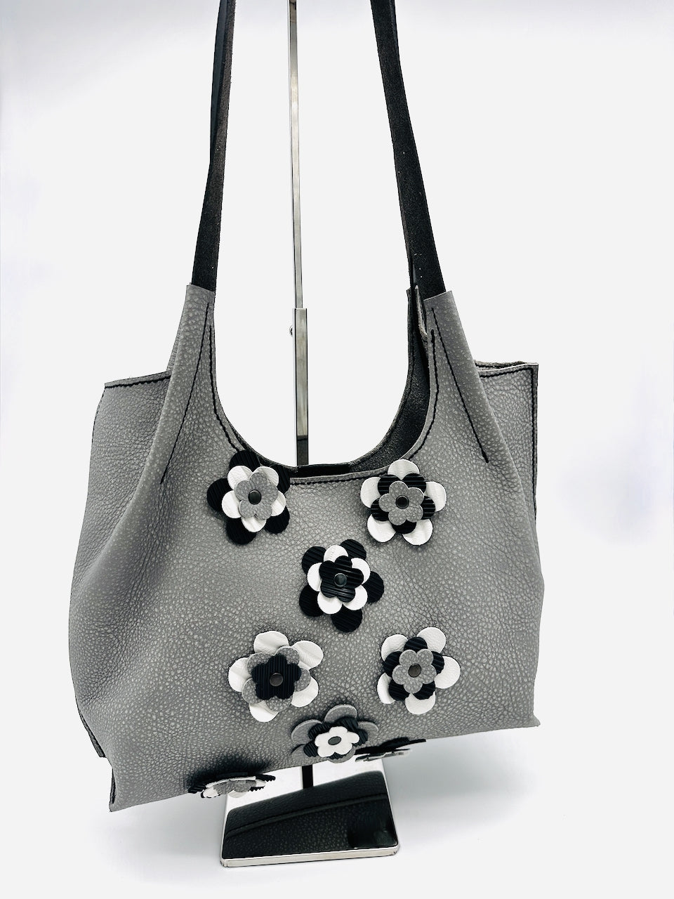 Gray leather handbag with floral appliqués on a white background